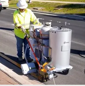 Máquina aplicadora de pintura termoplástica en operación