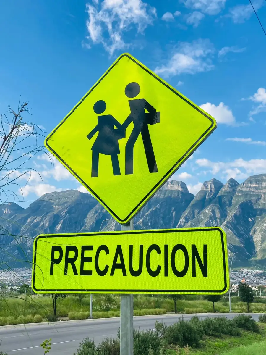 Señal escolar PRECAUCIÓN primer plano con cielo azul de fondo